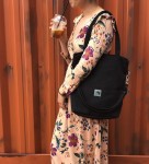 A black tote bag made of  thick woven fabric.